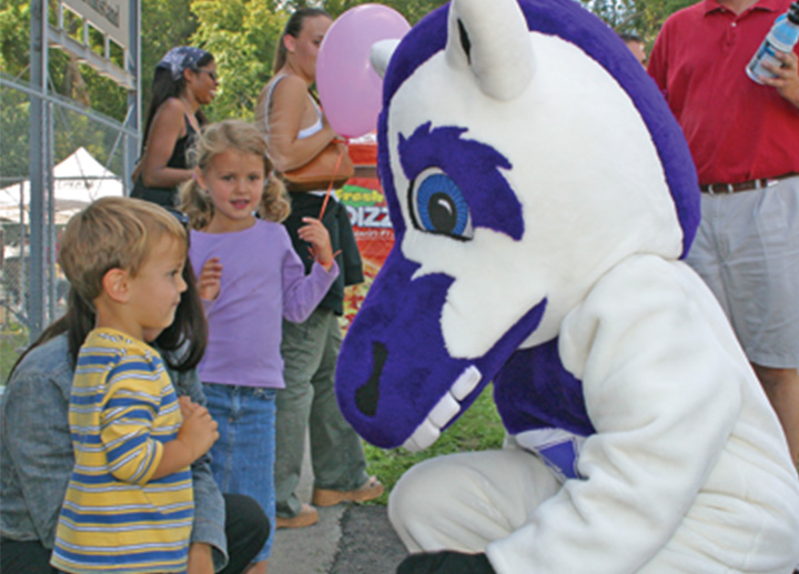 山ǿ's Mustang mascot talking to a child
