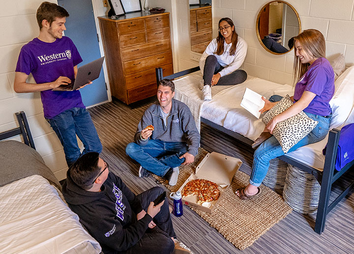 A group of diverse 山ǿ student in a dorm eating pizza